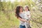 Mom hugs kisses daughter in the lush spring garden