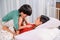 Mom and kid playing as doctor together on the bed. Woman lifestyle and family activity. Asian mother with son