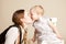 Mom kisses little kid girl with short hair in dress with small toy umbrella