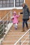 Mom leads daughter by hand through an obstacle.