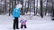 Mom leads hand of happy little daughter walking along snowy road. Baby and mother on winter walk. Mom with child on