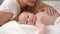 Mom lies with baby in bed and kisses. concept of maternal love, newborn care.