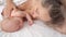 Mom lies with baby in bed kisses hands. concept of maternal love, newborn care.