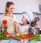 Mom and little daughter cooking vegeterian dish indoors