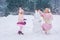 Mom and little daughter dressed in pink clothes have fun and make a snowman in a snowy park