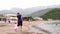 Mom and a little girl walk along the sandy beach, holding hands. Back view