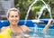 Mom plays with the baby by splashing a stream of water into him in the pool with clean water in the yard