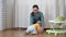 Mom plays with her newborn daughter sitting on the floor. A child crawls and plays with a pink rubber ball