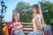 Mom presenting her cute daughter gift box on park bench