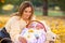 Mom put the child in a basket and crouched next to her, resting in the park