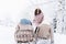 Mom rides little daughters on sled. Beautiful stylish sledding girls, sisters in winter snowy yard, park, forest. Hat, coat, scarf