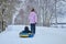 Mom rolls her little son on tubing in the Park in the winter. Happy family outdoors. winter fun for young children