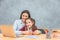 Mom and schoolgirl are sitting at the table smiling genuinely. Mom hugged her daughter. Sincere emotions.