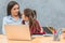 Mom and schoolgirl are sitting at the table. Speaking look one on one. The gray background.