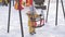 Mom shows curious newborn daughter a swing on a winter playground. The toddler is holding onto a baby swing and smiling.