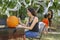 Mom sits at the carving table to draw the face on the  pumpkin while the kids add the spider webbing on the trees