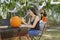 Mom sits at the pumpkin carving table to draw the face of the pumpkin while the kids add the spider webbing on the trees