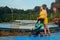 Mom with a small child in a stroller stands on a pontoon pier and looks at the sea while waiting for the boat. A woman in a yellow