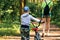 Mom and son with a bicycle stroll through the park, walk in the park