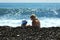 Mom and son in a blue panama play in the surf near the wet pebbles.