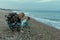 Mom and son in clothes collect shells on the seaside. The interaction of mother and child