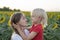 Mom and son make each other`s faces. Cheerful portrait of mother and son on sunflower field background