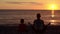 Mom and son meditate on the beach in lotus position. View from the back, sunset, silhouettes