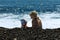 Mom and son play in the surf near the wet pebbles.