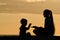 Mom and son are playing on the beach. Silhouettes at sunset