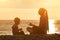 Mom and son playing on the beach with stones. Sunset time, silhouettes