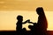 Mom and son playing on the beach with stones. Sunset time, silhouettes