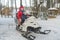 Mom and son sit on a snowmobile in the snow-covered forest winter fun