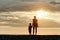 Mom and son are standing on the beach. Silhouettes at sunset