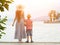 Mom and son standing on the pier on the sea background, lighthouse and mountains in the distance. Back view