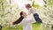 mom spinning with a daughter in her arms in the park by a flowering tree.