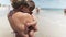 Mom in a summer bikini holds a baby who wants to sleep on the beach near the sea on vacation
