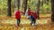 Mom swings children on a rope swing. Happy family in nature in autumn. two beautiful girls and the boy are happy and laugh.