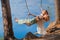 Mom swings with her daughter on a rope swing against the backdrop of a forest lake reflecting the sky. Family concept