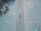 Mom takes her daughter on a sled in winter along the road at sunset in Paldiski, view down from a drone