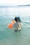 Mom taking boy with inflating ring into sea