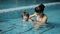 Mom teaches a child to swim in the pool.
