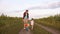 Mom teaches daughter to ride a bike on a country road in a field of sunflowers. a small child learns to ride a bike