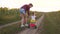 Mom teaches daughter to ride a bike on a country road in a field of sunflowers. a small child learns to ride a bike