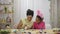 Mom teaches her daughter to paint eggs with paints and brush. African American woman and little girl with bunny ears are