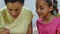 Mom teaches her daughter to paint eggs with paints and brush. African American woman and little girl with bunny ears are