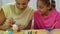 Mom teaches her daughter to paint eggs with paints and brush. African American woman and little girl with bunny ears are