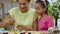 Mom teaches her daughter to paint eggs with paints and brush. African American woman and little girl with bunny ears are