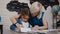 Mom teaches her daughter to write first letters. Teacher and student perform homework in elementary school. Young blonde