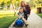 Mom teaches her son to ride a toy car in the park. Preschooler driving his toy car outdoors in summer