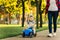 Mom teaches her son to ride a toy car in the park. Preschooler driving his toy car outdoors in summer